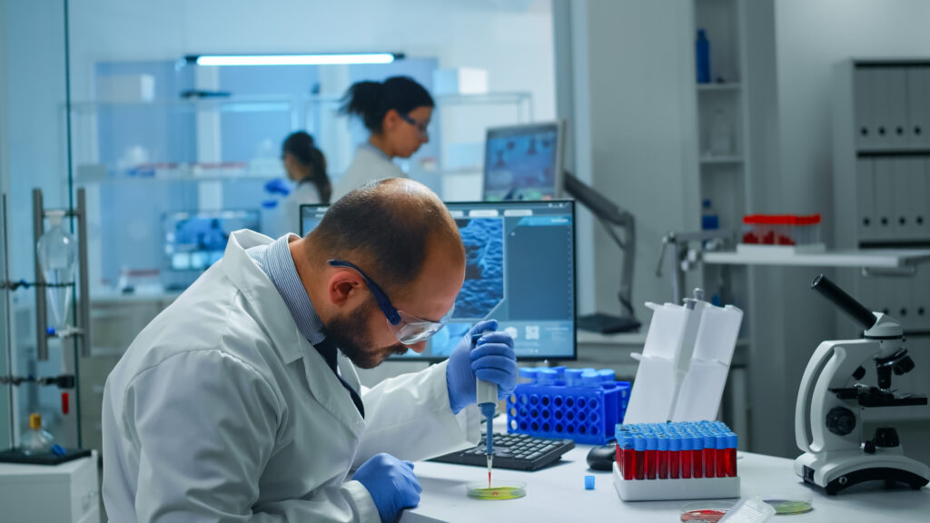 scientist examining drug discovery putting blood sample in petri dish with micropipette.