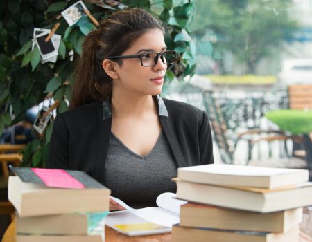pensive female student sitting at table with books