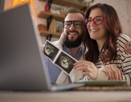side view couple announcing pregnancy with laptop